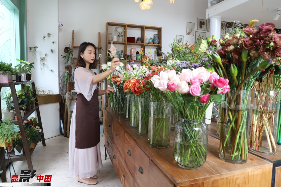 王黎媛是一名河南姑娘，在昆明念完大學(xué)后，就再也舍不下春城的藍(lán)天陽(yáng)光、青山碧水，更舍不下這里的四時(shí)繁花，于是就干脆留了下來(lái)，成了一名媒體人。2017年的時(shí)候又毅然辭去工作，創(chuàng)業(yè)開(kāi)起了花店，成了都市里的一名“花房姑娘”。圖為王黎媛在自己的花店中整理鮮花。新華網(wǎng) 周亞平/攝 念新洪/文